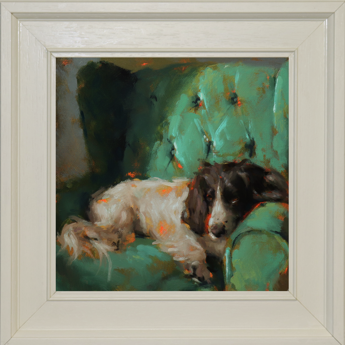 A framed painting of a black and white dog resting on a green tufted chair, with a wide off-white frame surrounding the artwork.