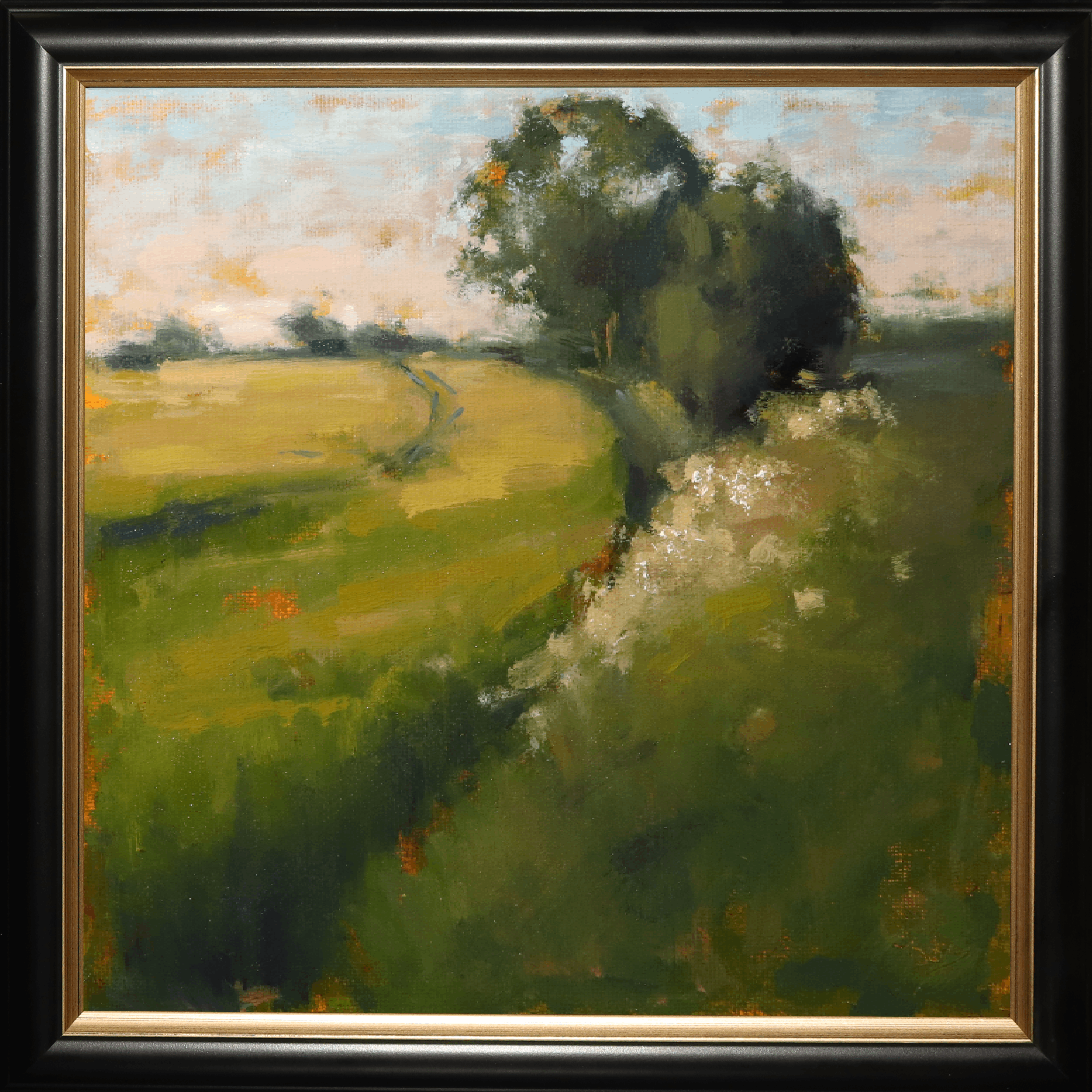 A framed landscape oil painting featuring a green field with a winding path, a prominent dark tree, and a pale sky, enclosed in a black frame with a gold inner border.