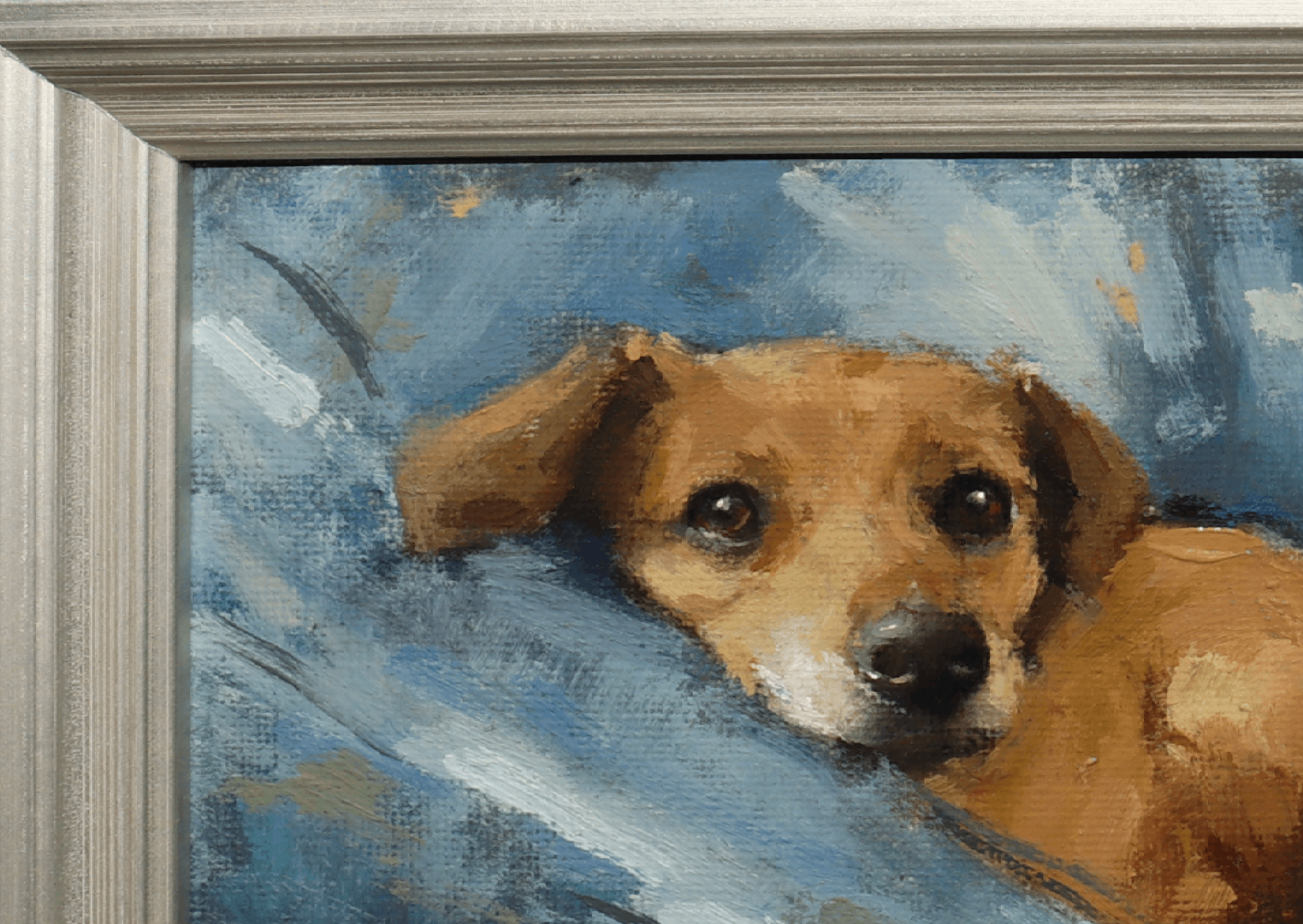 A close-up of a framed painting depicting a brown dog resting on a blue textured background, with a silver-toned frame visible on the left and top edges.