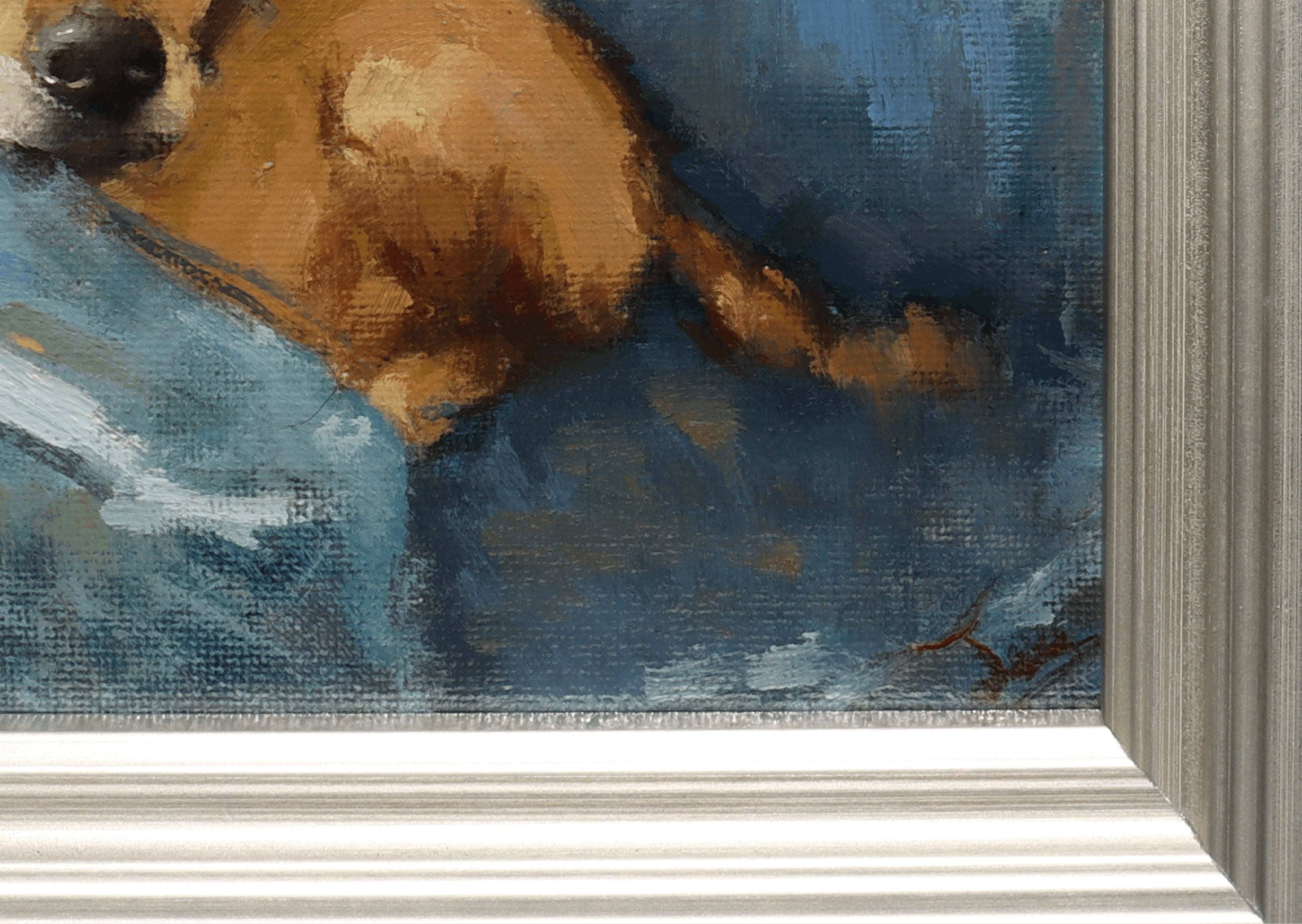 Close-up of a framed painting showing part of a brown dog resting on a blue surface, with a white frame visible at the bottom and right edge.