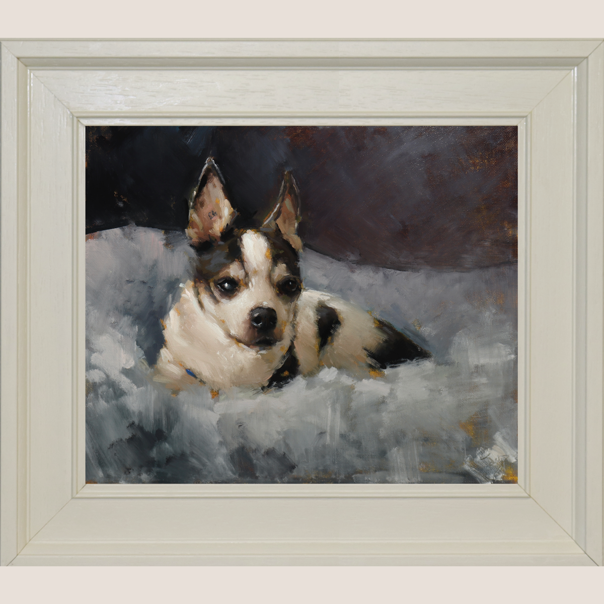 A framed portrait painting of a small black-and-white dog lying on a gray and white textured surface, with a dark painted background. The artwork is presented in a wide, light-colored wooden frame against a plain light beige wall.