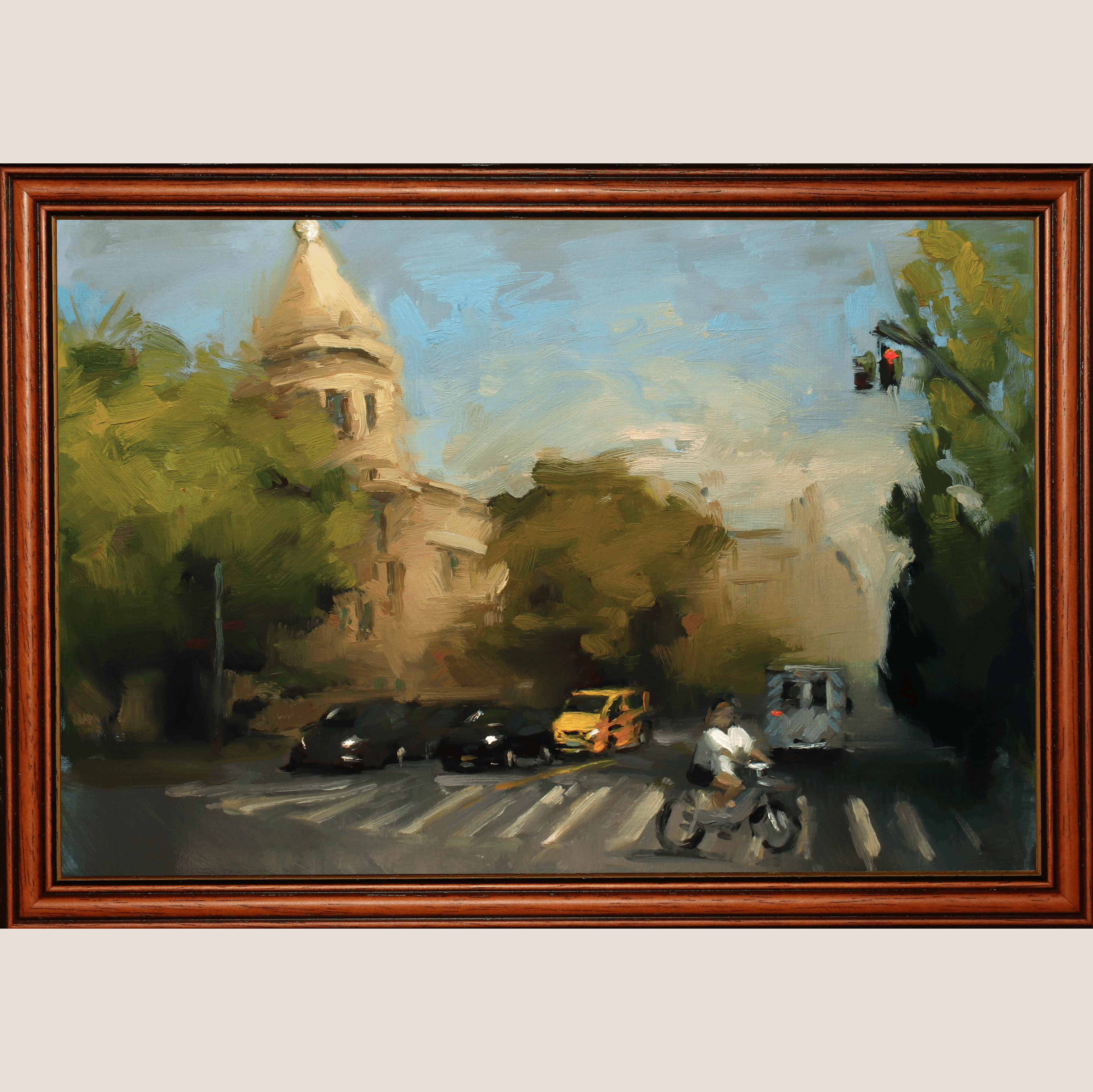 A framed oil painting depicting a street scene with a cyclist, cars, trees, and a building dome under a blue sky, enclosed in a dark brown wooden frame.