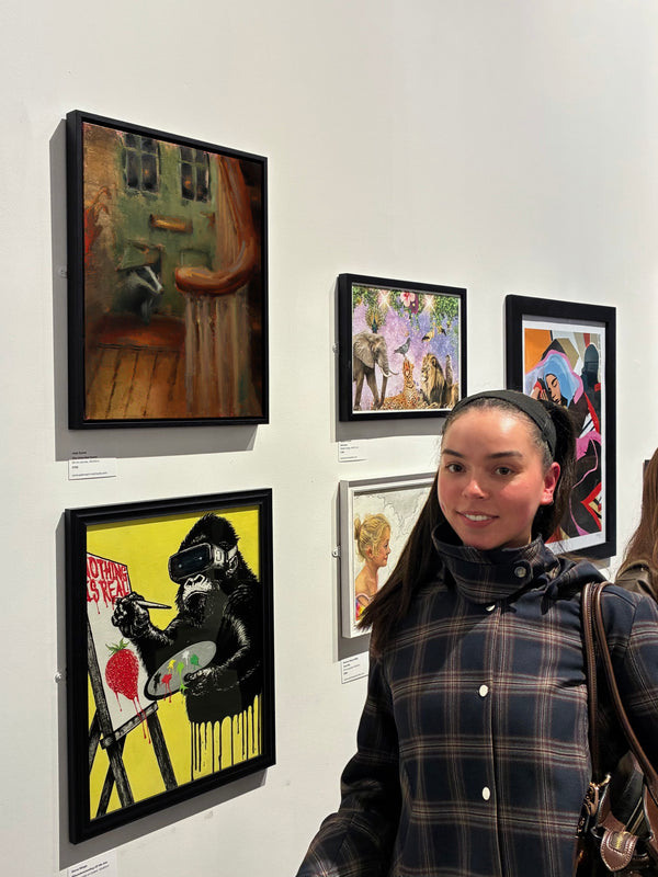 Woman standing in front of framed artworks on a wall