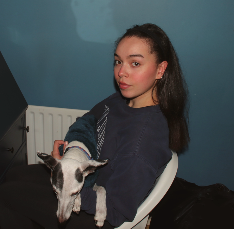 Woman holding a dog in a room with a blue wall and radiator.