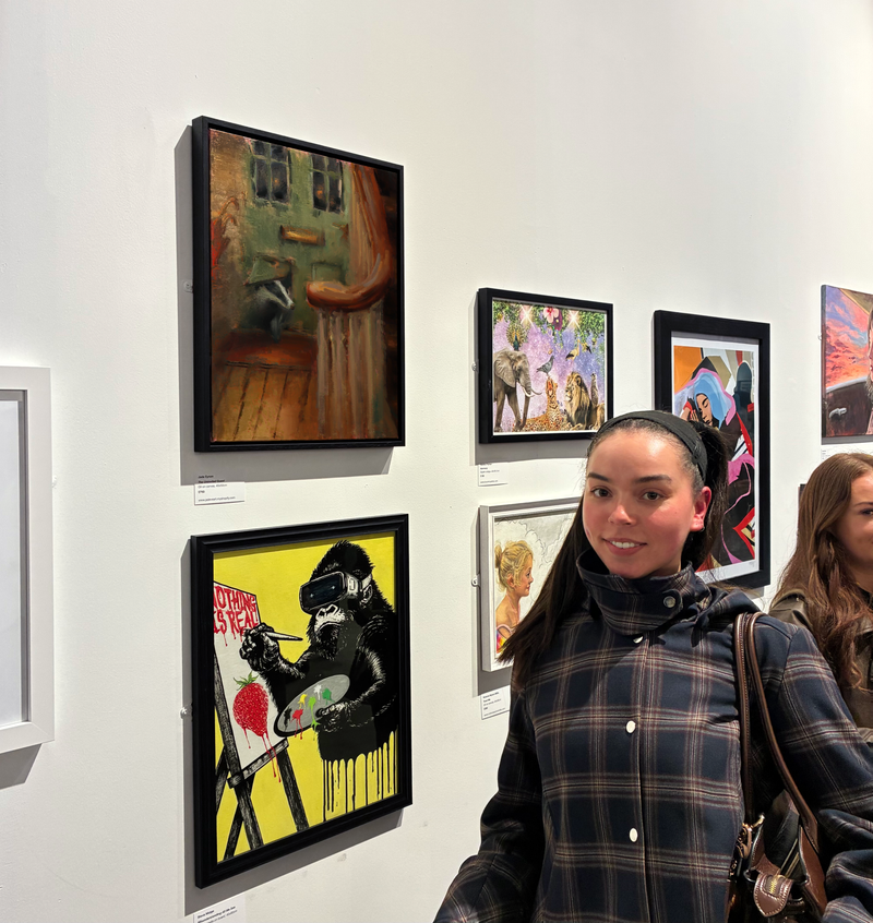 Woman standing in front of framed artworks on a wall