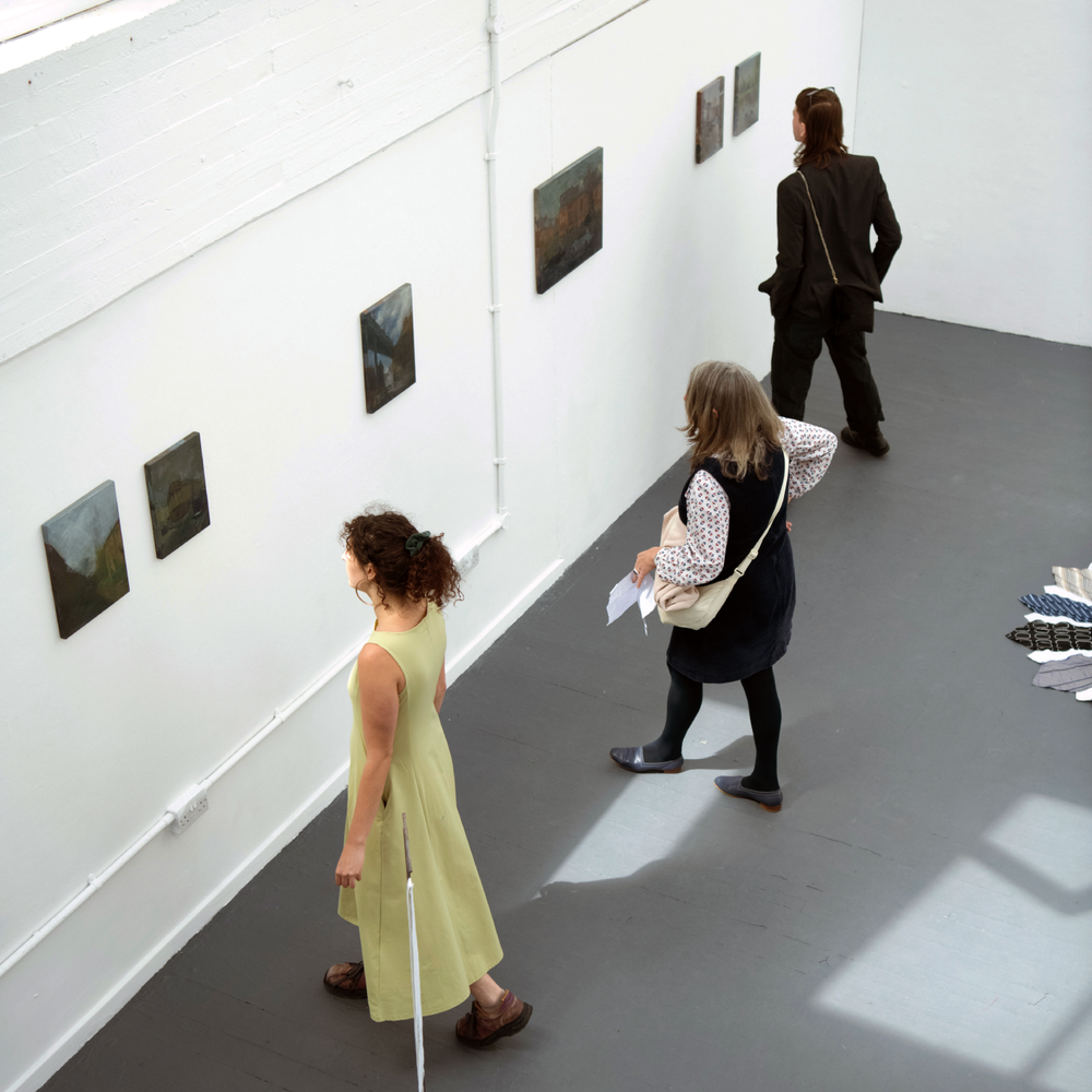 People in an art gallery observing artworks on the wall.