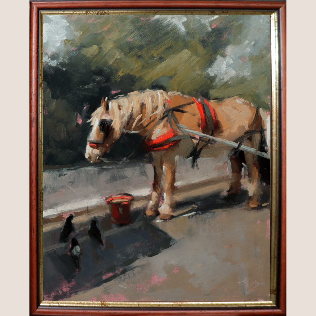 A framed oil painting depicting a light brown horse wearing red harnesses, standing beside a small red bucket on a street with crows in the foreground. The painting is enclosed in a reddish-brown wooden frame with gold-toned inner trim, shown against a light beige background.